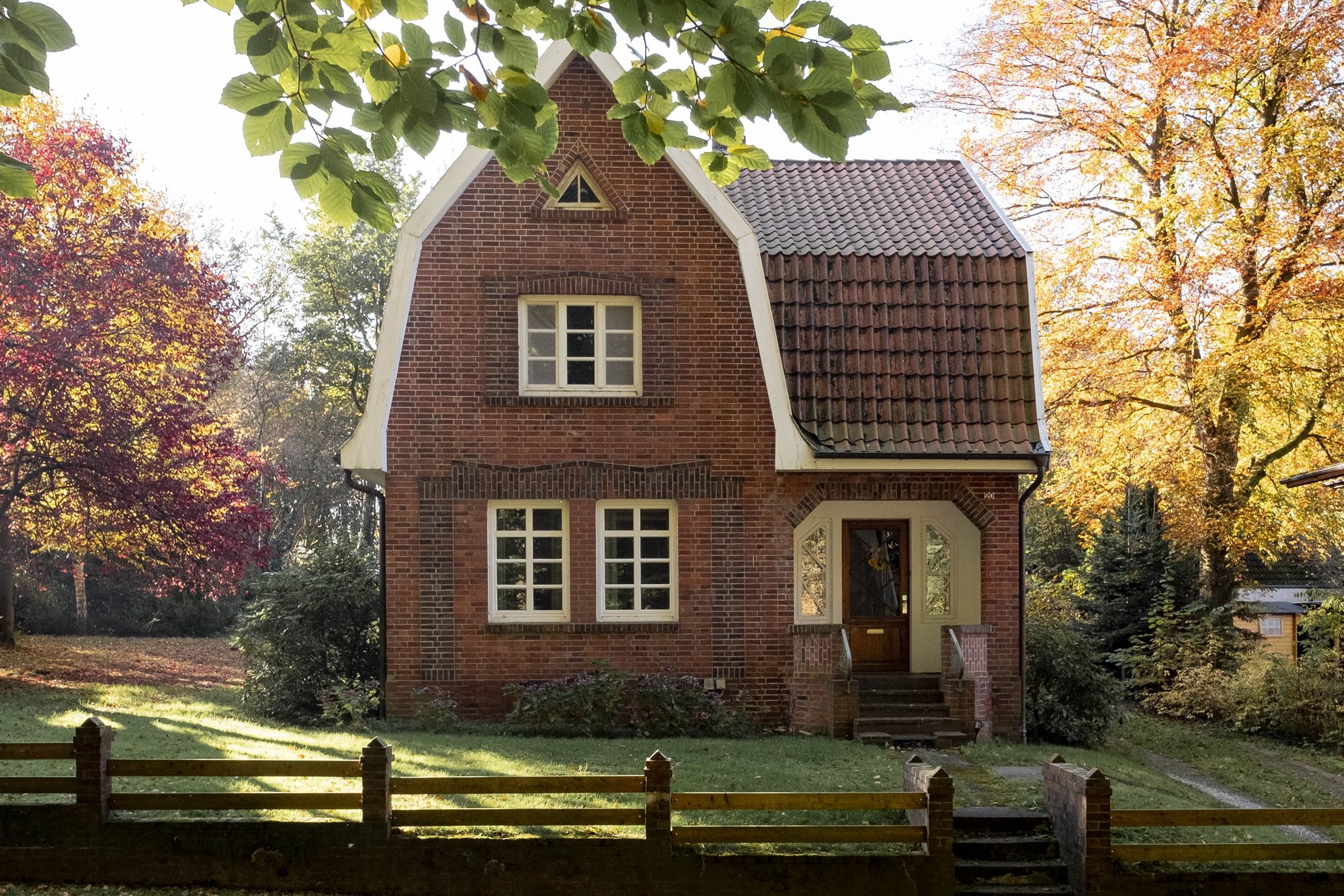 Das Backsteinhaus Wassermühle im Herbstlicht, umgeben von bunten Bäumen