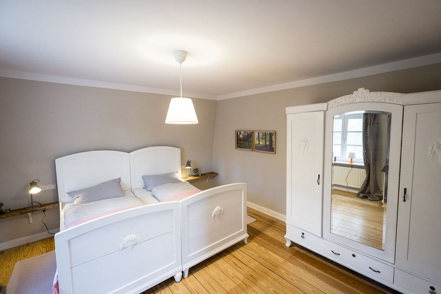 Schlafzimmer mit weißem Bett und Kleiderschrank
